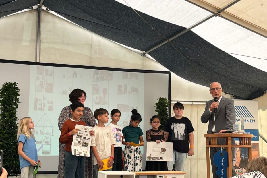 Schülerinnen und Schüler stehen gemeinsam mit der Pädgogin und einem Mann auf der Bühne