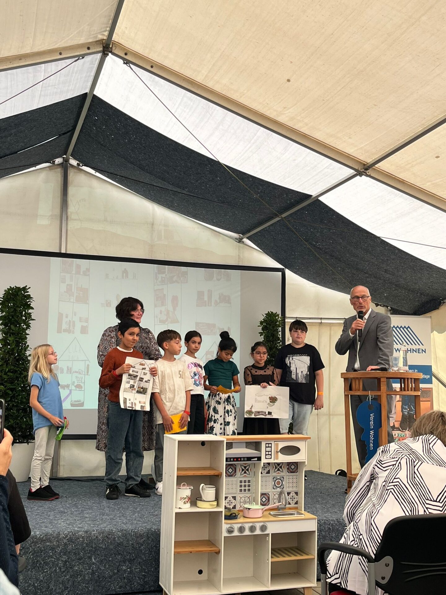 Schülerinnen und Schüler stehen gemeinsam mit der Pädgogin und einem Mann auf der Bühne