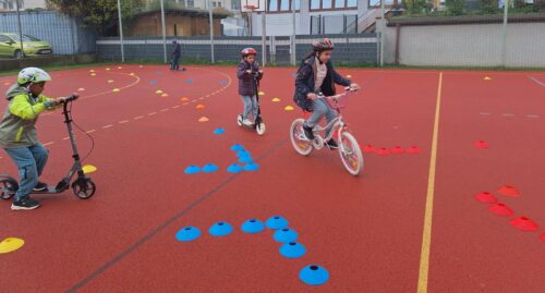 Kind mit Roller und Kind mit Fahrrad fahren durch den aufgebauten Parcour