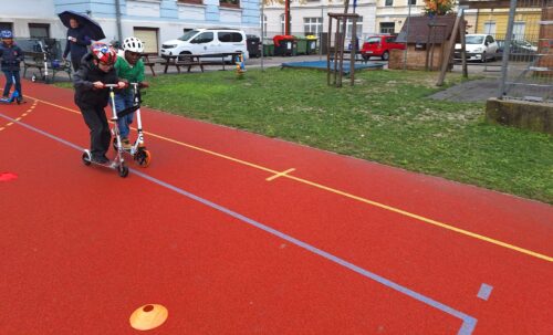 Kinder fahren mit dem Roller um die Wette und versuchen eine Zielbremsung