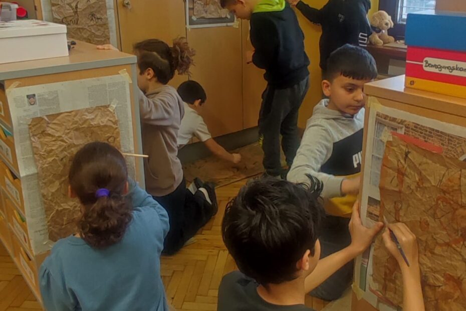 Kinder zeichnen mit Kohle auf Plakaten, die an der Wand montiert sind