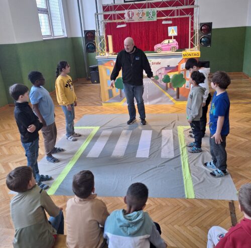 Die Kinder zeigen das richtige Überqueren des Zebrastreifens