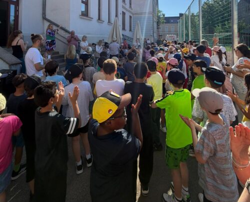 Die Beteiligten stehen vor den Stiegen und hören der Schulleiterin bei der Eröffnung des Aktiv-Kreativ-Tages zu.
