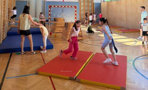 Kinder probieren im Turnsaal verschieden aufgebaute Stationen aus