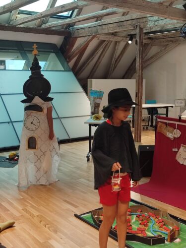 Ein Kind trägt einen Hut und eine kleine Laterne neben der Kirche und dem 3D-Modell von St.Pölten