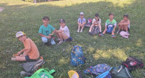 Kinder sitzen im Gras und machen Pause