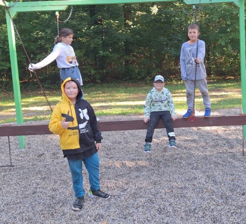 Kinder sitzen auf einem Spielgerät am Spielplatz