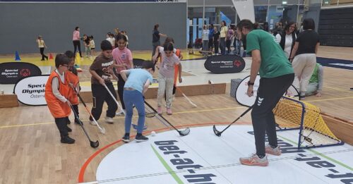 Kinder spielen mit einem Erwachsenen Floorball