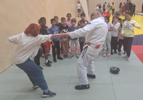 Ein Judotrainer zeigt den Kindern einen Befreiungsgriff mit einer Lehrperson