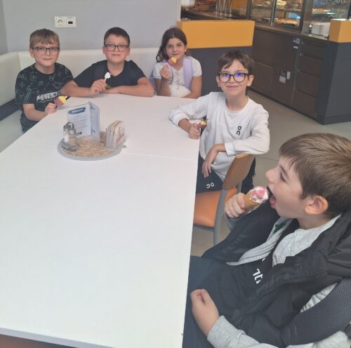 Kinder sitzen beim Tisch und essen Eis