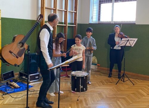 2 Kinder dürfen während einem Mitmachkonzert im Turnsaal die Trommel spielen