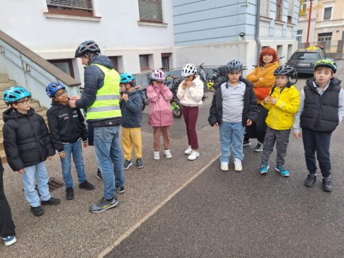 Die Kinder üben mit Hilfe eines Erwachsenen das richtige Aufsetzen des Radhelms.