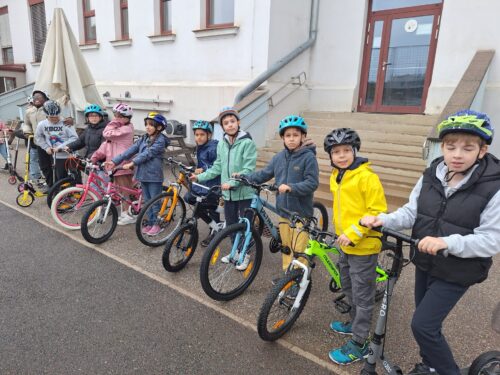 Die Kinder stehen mit ihren Rädern und Rollern im Hof in einer Reihe