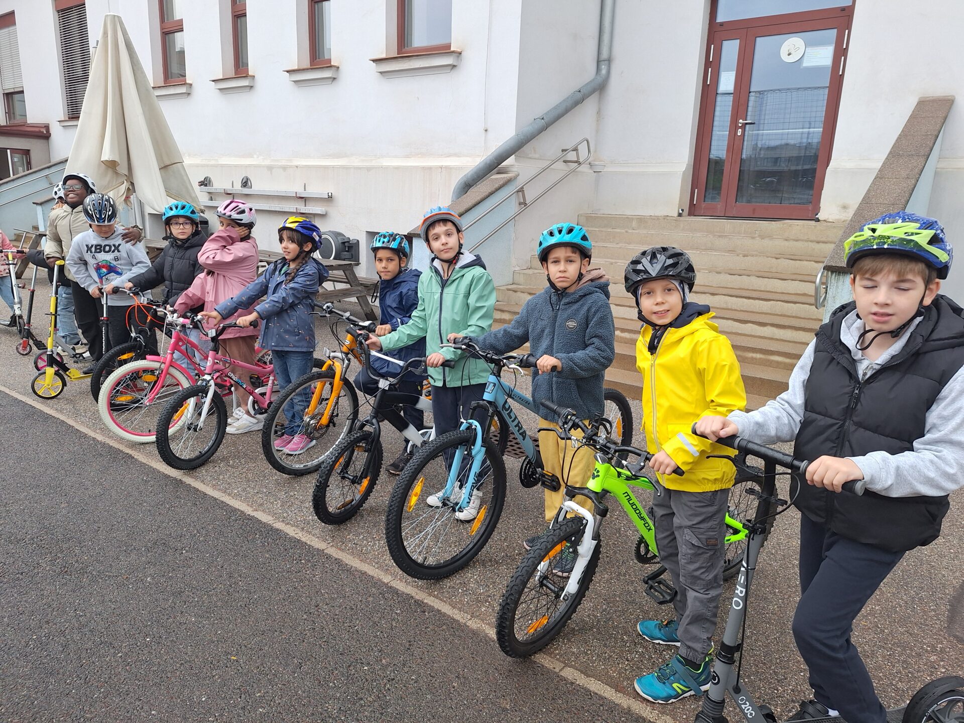 Die Kinder stehen mit ihren Rädern und Rollern im Hof in einer Reihe