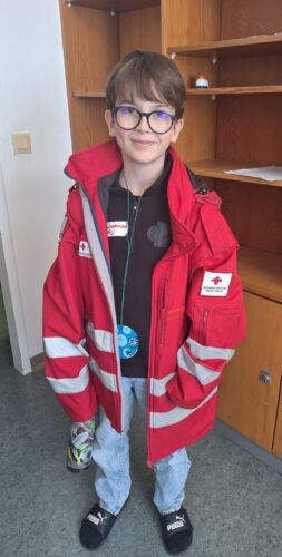 Ein Junge trägt eine zu große Jacke von einem Rettungssanitäter