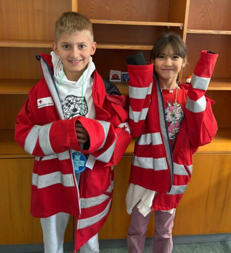 2 Kinder tragen zu große Jacken von Rettungssanitätern