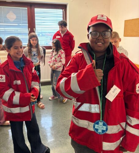 2 Kinder tragen zu große Jacken von Rettungssanitätern