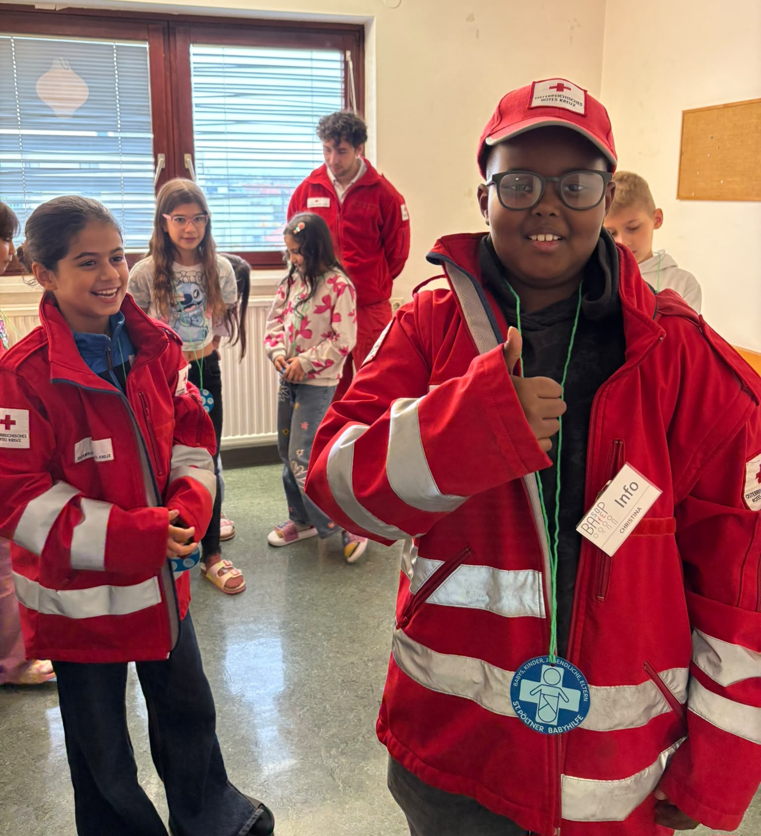 2 Kinder tragen zu große Jacken von Rettungssanitätern